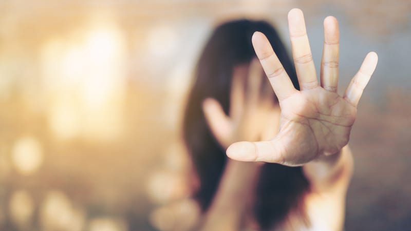 Woman shielding her face, illustrating a sign of an abusive relationship Woman shielding her face, illustrating a sign of an abusive relationship
